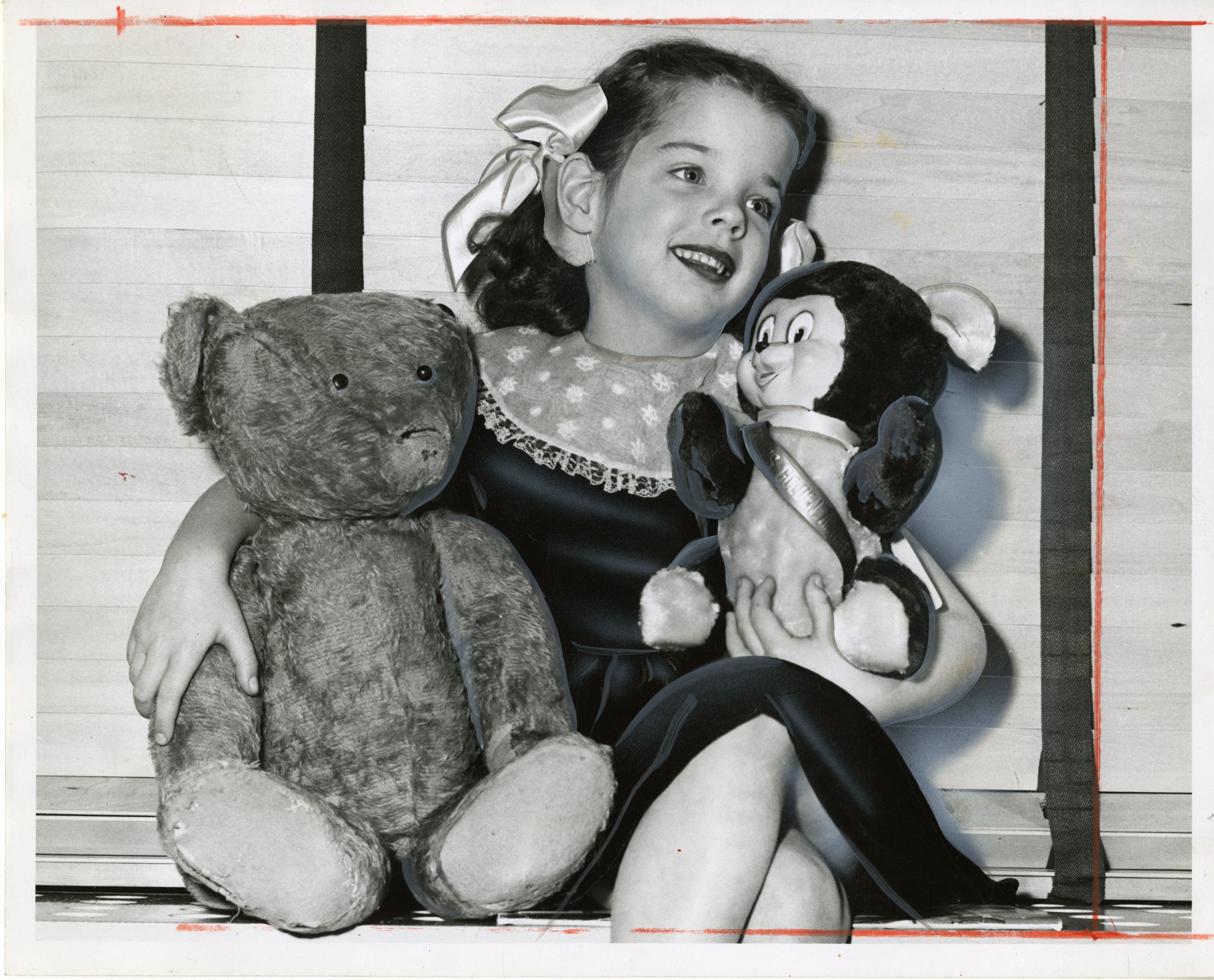 black-and-white photograph of child in center holding two teddy bears in each arm