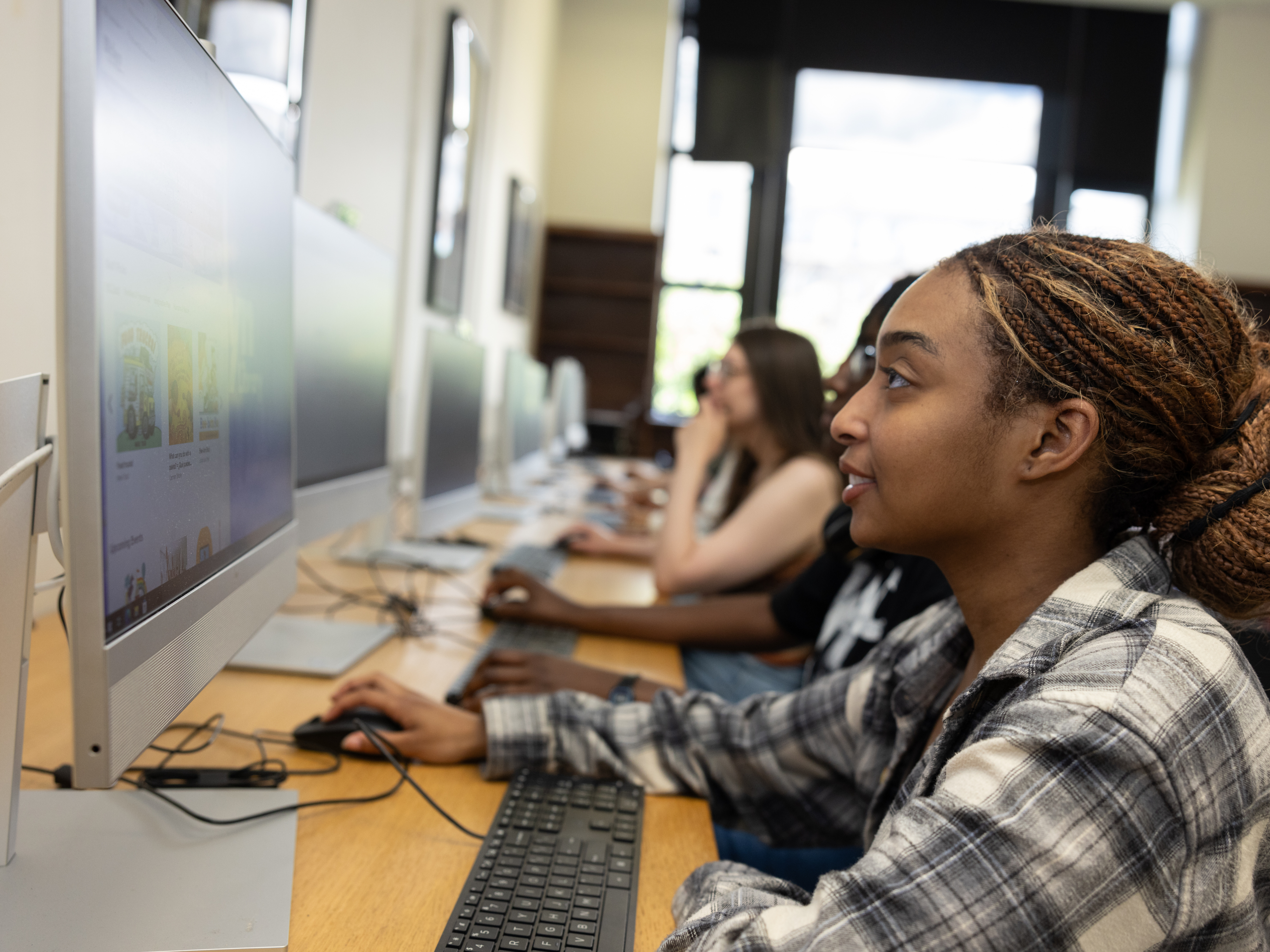 A teen girl sits at a computer in a lab.