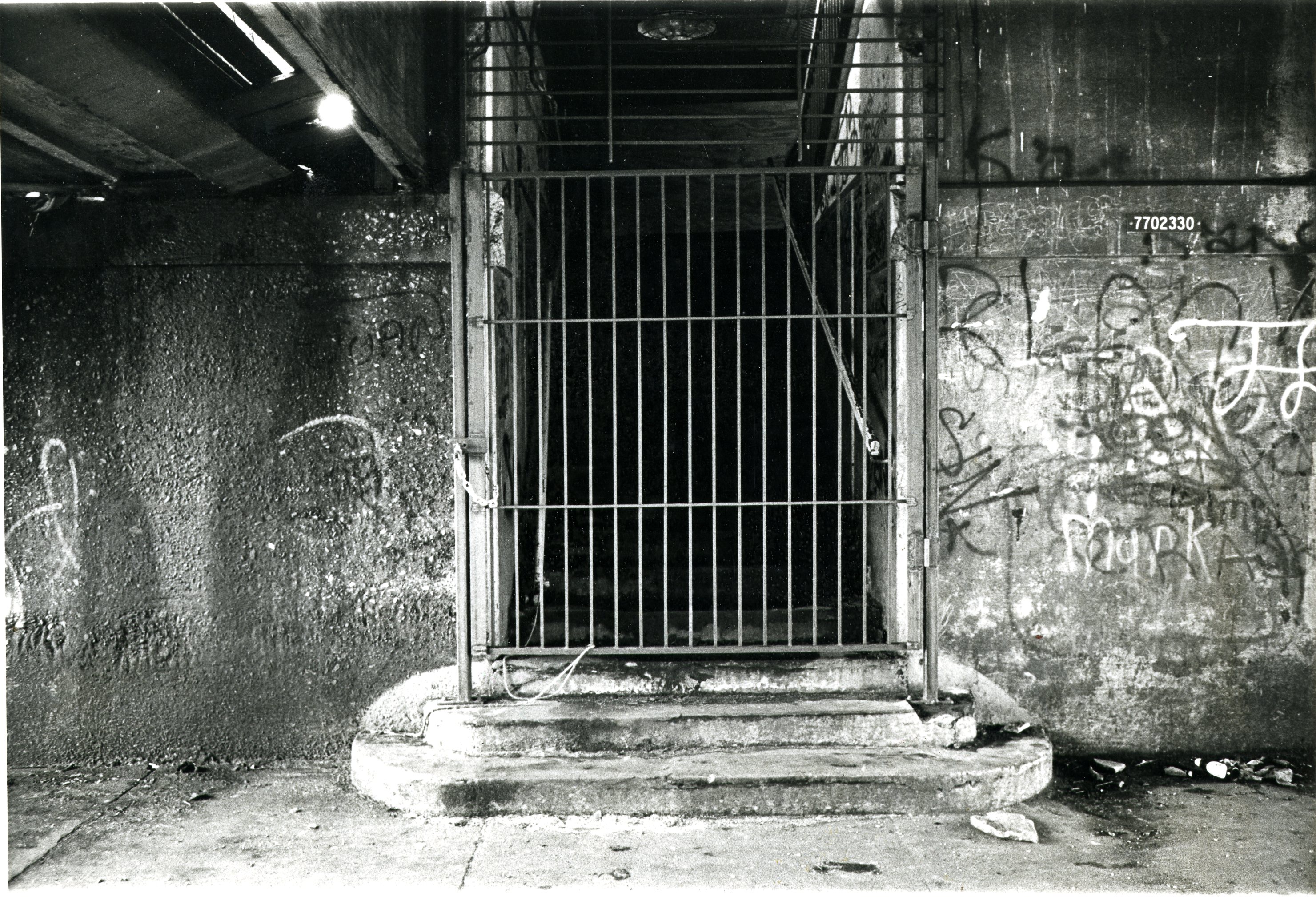 Gate of closed subway station. concrete walls on either side of entrance have graffiti