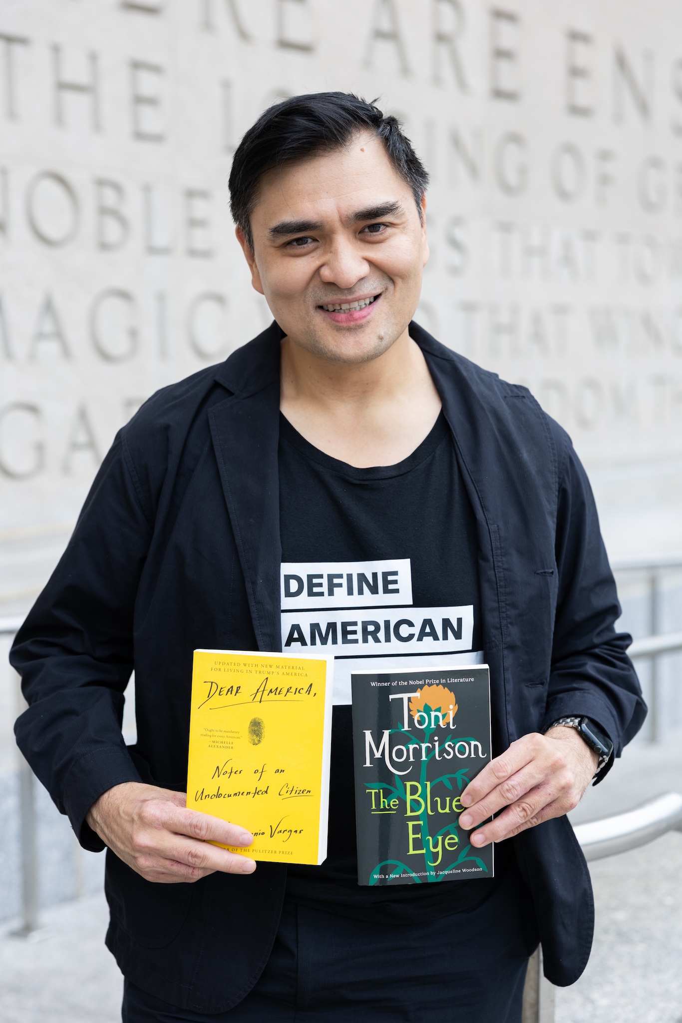 a headshot of Jose Antonio Vargas holding Dear America and The Bluest Eye by Toni Morrison