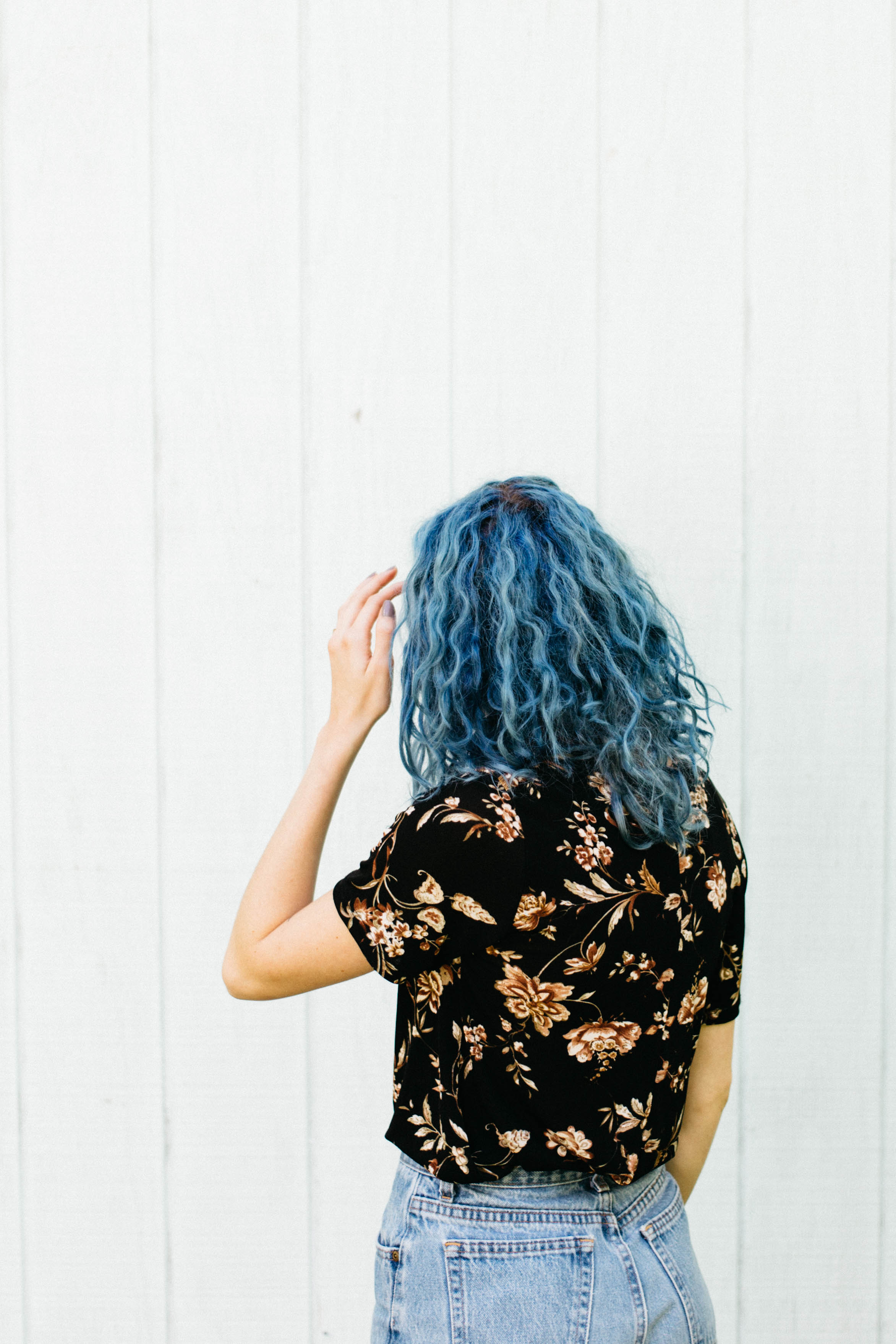girl with blue hair standing infront of a wall