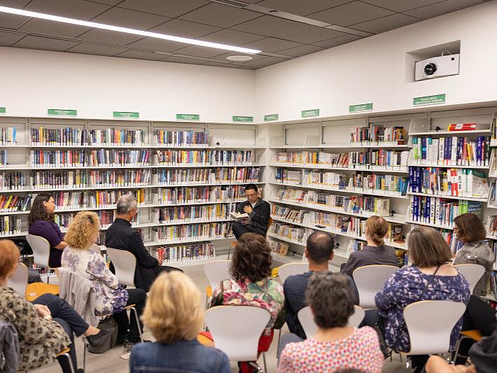Hua Hsu speaks to a room full of people in a library