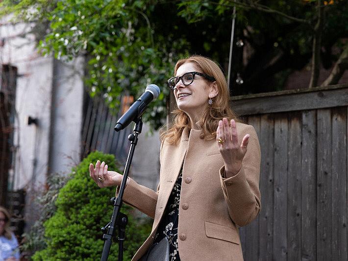 Melissa Clark speaks into a microphone at an outdoor event. 