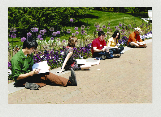 five young people sitting on ground in garden sketching