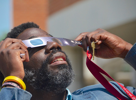 Person using solar eclipse glasses to safely view the solar eclipse.