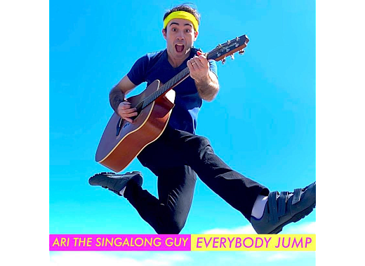 Ari the Singalong Guy jumping while playing an acoustic guitar