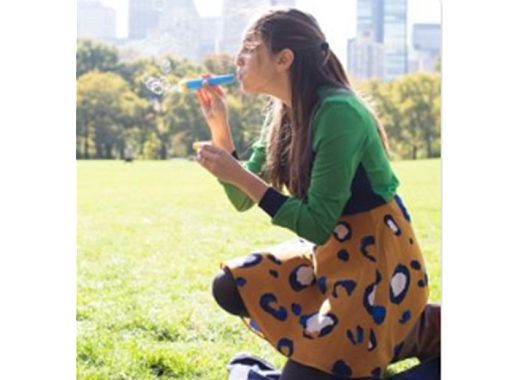 profile of a woman blowing bubbles, outdoors, city scape in background, 