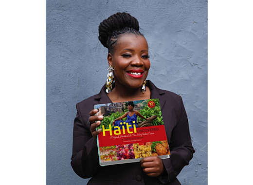 a woman holding a haitian cookbook