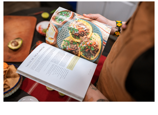 Image of someone looking at a cookbook with the page opened to a taco recipe