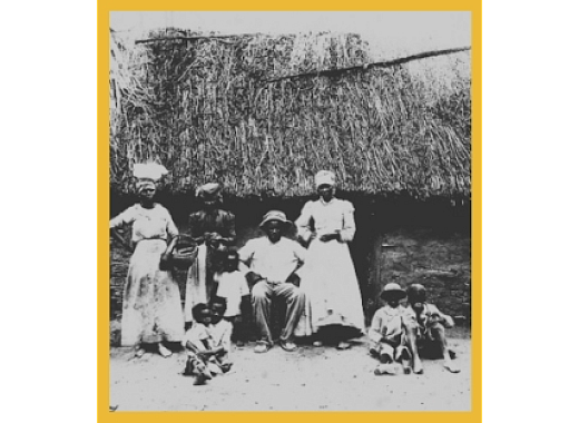 black and white photo of people in front of a thatched roof building