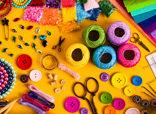 brightly colored craft supplies scattered on a solid yellow background