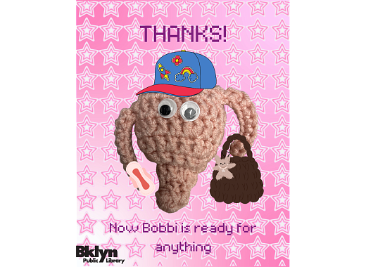A crocheted uterus dressed up in a hat, purse and a pad